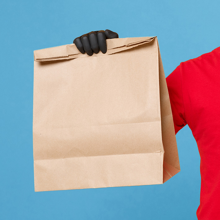 food delivery person holding a brown paper bag